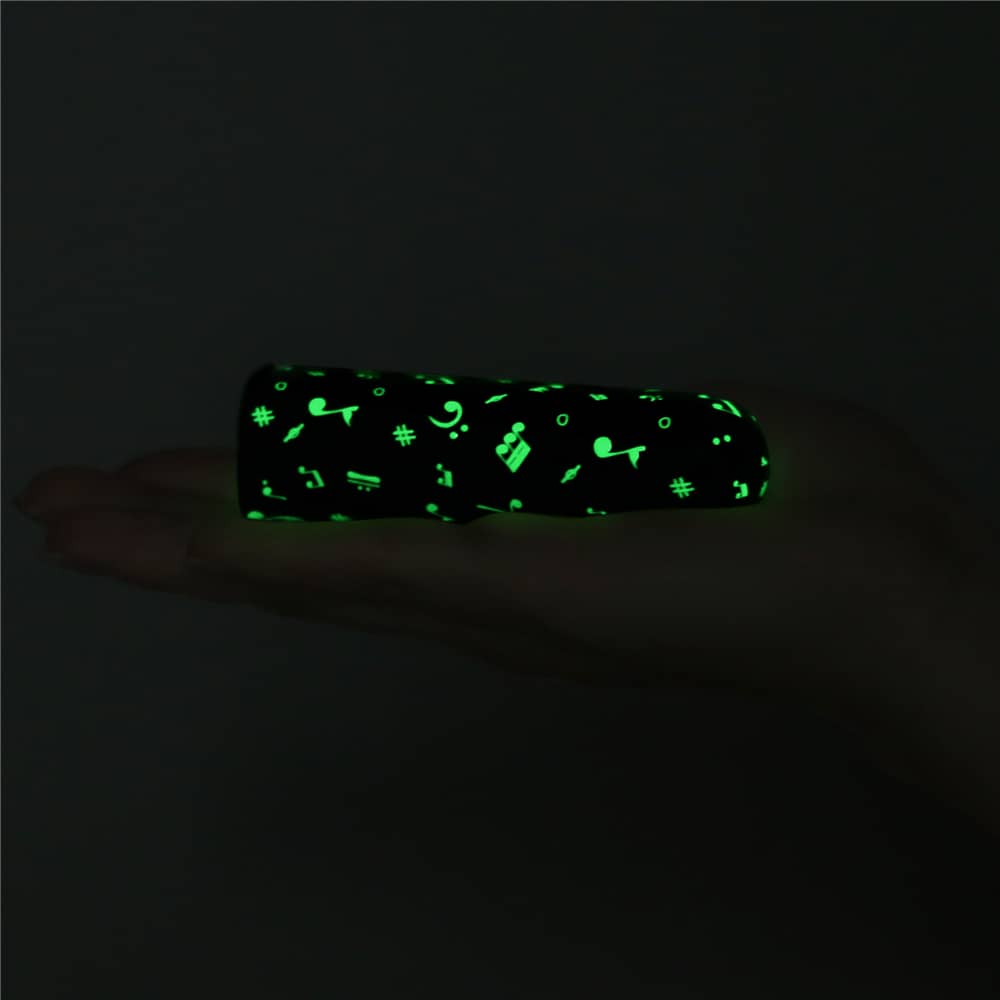The rechargeable luminous massager glowing in the dark lays flat on the palm